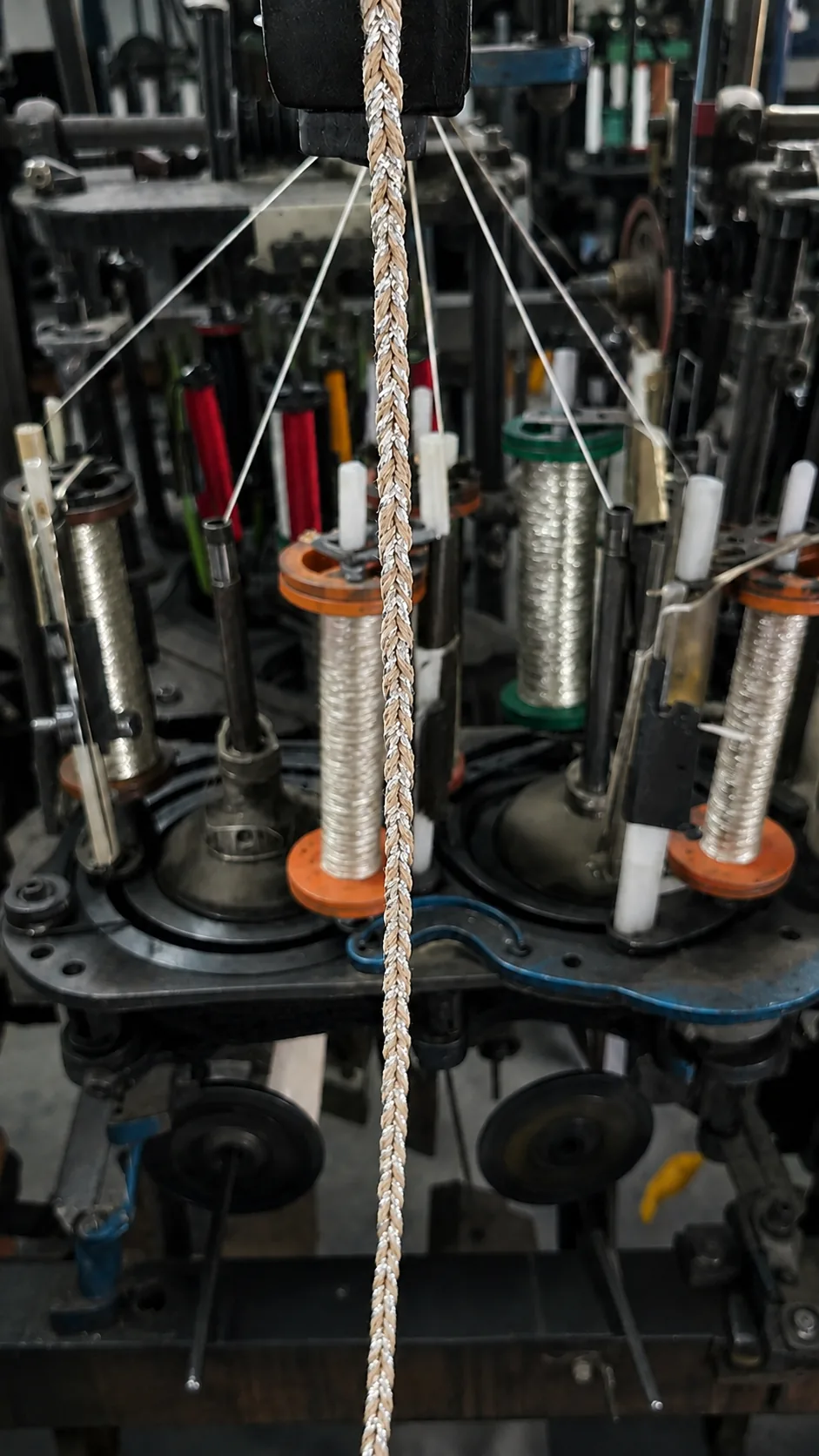Cord braiding machine running with thread spools at the Saras Udyog factory in Jaipur, India